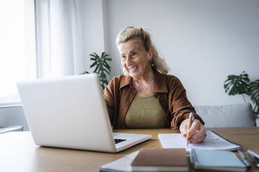 Glücklicher älterer Freiberufler bei einem Videogespräch am Laptop im Büro zu Hause - AAZF00011