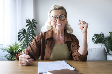 Lächelnde Freiberuflerin mit Vitiligo-Haut am Schreibtisch im Heimbüro - AAZF00014