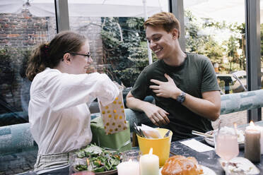 Woman surprising brother with gift while sitting at restaurant - MASF34714