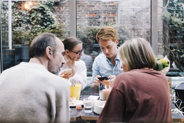 Siblings sharing smart phones during birthday party at restaurant - MASF34730