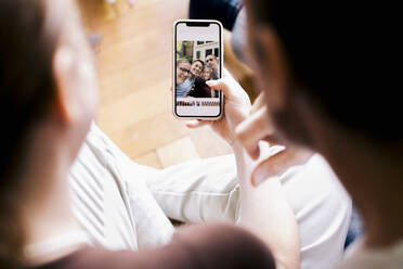 Geschwister schauen sich ein Familienfoto auf dem Smartphone an - MASF34747