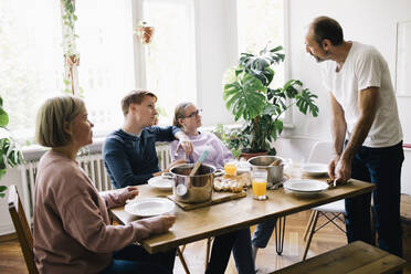 Familie im Gespräch mit Vater, der zu Hause am Tisch steht - MASF34749