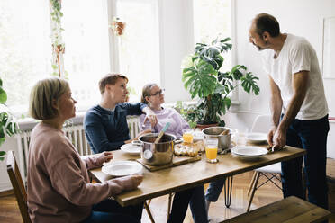 Family talking with dad standing near table at home - MASF34749