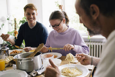 Glückliche Familie genießt das gemeinsame Essen am Esstisch zu Hause - MASF34751