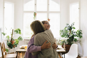 Parent embracing daughter while standing at home - MASF34759