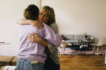 Rear view of girl embracing mother standing at home - MASF34760