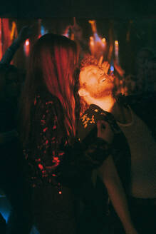Junge männliche und weibliche Freunde tanzen in einem Club während einer Wochenendparty in der Nacht - MASF34770