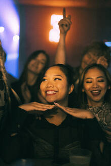 Glückliche junge Frau genießt beim Tanzen mit Freunden im Club in der Nacht während des Wochenendes - MASF34777