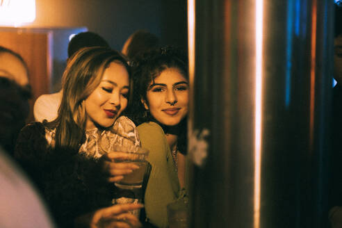 Glückliche weibliche Freunde tanzen, während sie in einem Club in der Nacht genießen - MASF34778