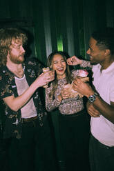 Cheerful young multiracial friends eating wrap sandwiches together at nightclub - MASF34791