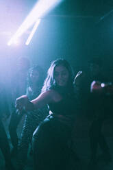 Young woman dancing against friends in background at nightclub - MASF34801