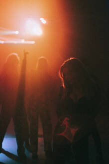 Junge Frau tanzt im Dunkeln mit rotem Scheinwerfer in einem Nachtclub - MASF34805