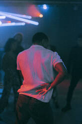 Rückansicht eines tanzenden jungen Mannes unter rotem Licht in einem Nachtclub - MASF34806