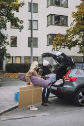 Mature couple loading luggage in car trunk during house relocation - MASF34908