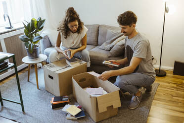 Freund und Freundin unterhalten sich beim Auspacken von Kartons im heimischen Wohnzimmer - MASF34957