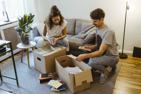 Freund und Freundin unterhalten sich beim Auspacken von Kartons im heimischen Wohnzimmer - MASF34957