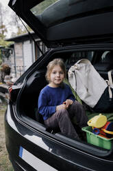 Porträt eines im Kofferraum eines Elektroautos sitzenden Mädchens - MASF34979