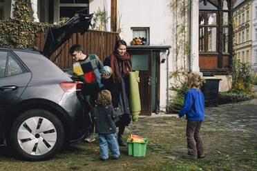 Familie lädt Sachen ins Elektroauto und bereitet sich auf ein Picknick vor - MASF34984