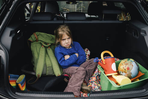 Angry girl with arms crossed sitting in electric car trunk - MASF34992