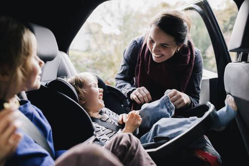Glückliche Mutter kitzelt Tochter im Auto sitzend - MASF35000