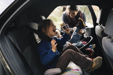 Side view of girl screaming while sitting at back seat of car - MASF35001