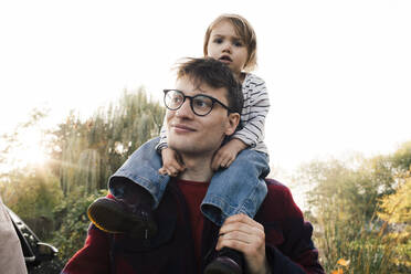 Lächelnder Vater mit Brille, der seine Tochter auf der Schulter trägt - MASF35013