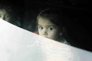 Porträt eines Mädchens im Kofferraum eines Autos, gesehen durch die Heckscheibe - MASF35014