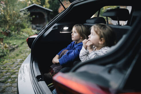 Mädchen, das im Kofferraum eines Elektroautos sitzt und von seiner Schwester träumt - MASF35015