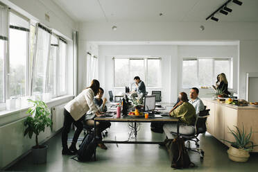 Geschäftskollegen, die am Schreibtisch sitzend im Büro diskutieren und planen - MASF35114