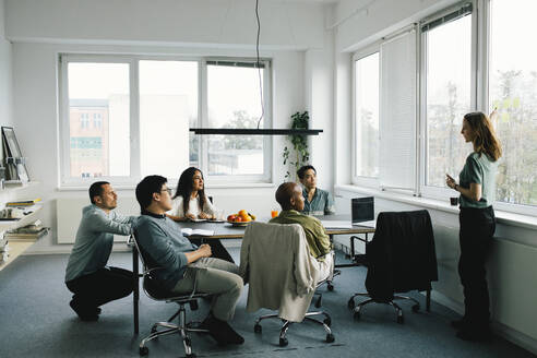 Geschäftsfrau beim Brainstorming mit männlichen und weiblichen Kollegen während einer Sitzung im Büro - MASF35122