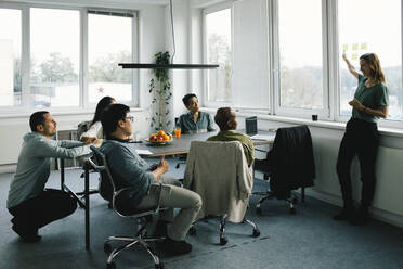 Businesswoman conducting meeting with colleagues sitting at desk in office - MASF35123