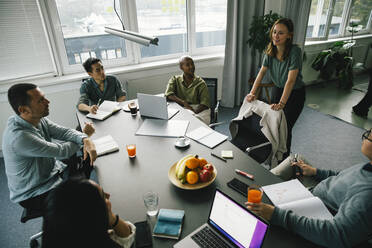 Geschäftsfrau diskutiert in Brainstorming-Sitzung mit multirassischen Kollegen am Schreibtisch im Büro - MASF35128