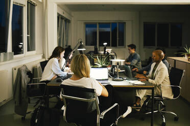 Geschäftskollegen, die bis spät in die Nacht am Schreibtisch im Büro sitzen - MASF35135