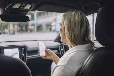 Mature woman using smart phone while sitting in front passenger seat - MASF35137