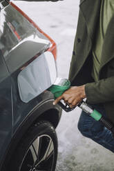 Midsection of man refueling car at fuel station - MASF35142