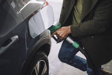 Low section of mature man refueling car while standing at gas station - MASF35143