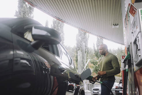 Älterer Mann, der an einer Tankstelle sein Fahrzeug auftankt - MASF35147