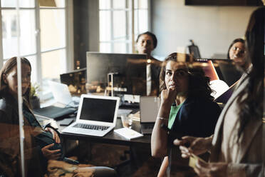 Female colleagues looking at mature entrepreneurs during business meeting in office - MASF35230