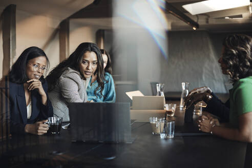 Geschäftsfrauen führen eine Besprechung am Laptop am Schreibtisch im Büro durch - MASF35250