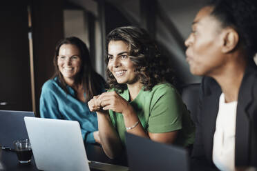 Smiling businesswoman with female colleagues during meeting at office - MASF35254