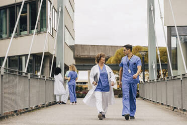 Weiblicher Arzt im Gespräch mit Krankenhauspersonal auf einer Brücke - MASF35312