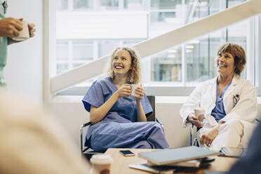 Happy female healthcare workers having coffee during break in hospital - MASF35321