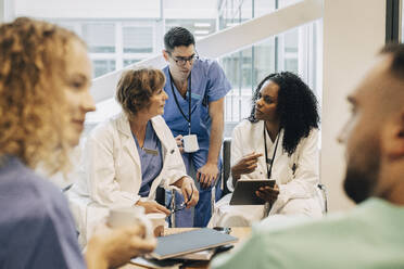 Ärztin mit Tablet-PC im Gespräch mit Kollegen während der Kaffeepause im Krankenhaus - MASF35326