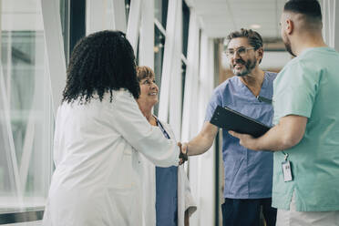 Male physician doing handshake with female colleague at hospital - MASF35337