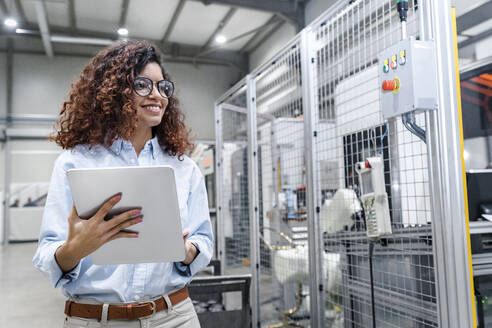 Happy engineer with tablet PC standing in industry - AAZF00034