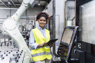 Glücklicher Ingenieur mit Tablet-Computer an einer Maschine in einer Fabrik - AAZF00048