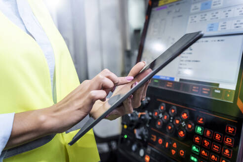 Hands of engineer using tablet PC by machine in industry - AAZF00050