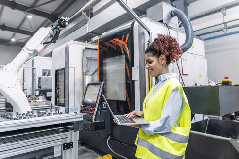 Happy engineer using laptop in factory - AAZF00055