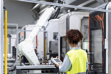 Ingenieur, der einen Roboterarm mit Ausrüstung in einer Fabrik steuert - AAZF00062