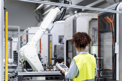 Engineer controlling robotic arm with equipment in factory - AAZF00062